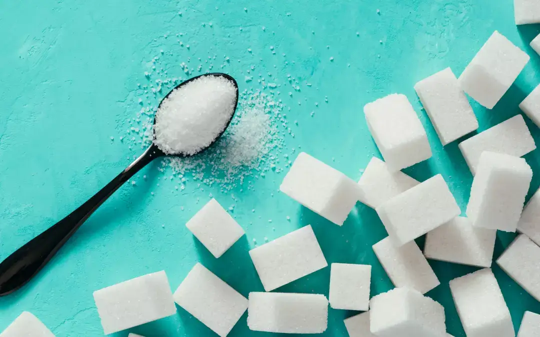 sugar cubes and a spoon full of sugar on a light blue background
